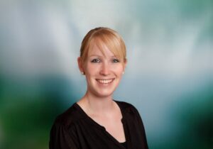 Elternstimme zur Schlafberatung: lächelnde Mutter vor grünem Hintergrund – positive Erfahrung mit bindungsorientierter Schlafberatung online für Babys & Kleinkinder.